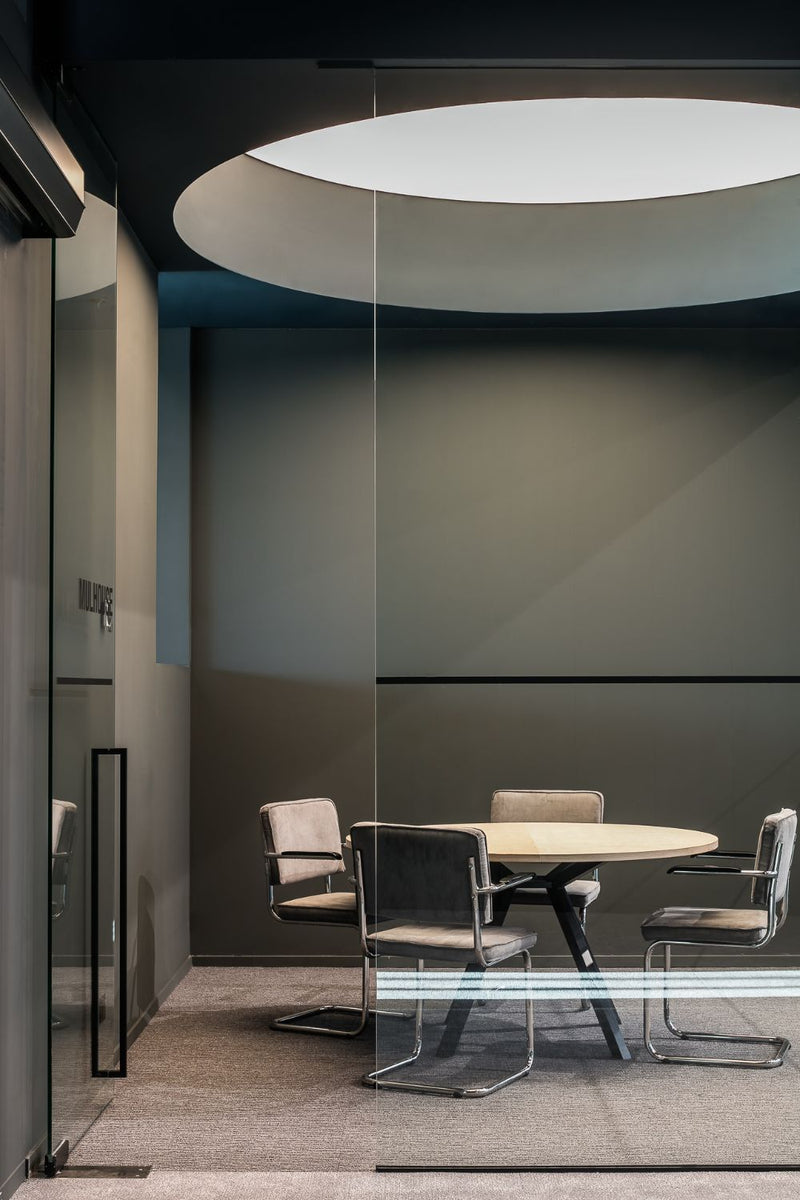 Modern conference room with a round table and chairs in a minimalistic office setting.